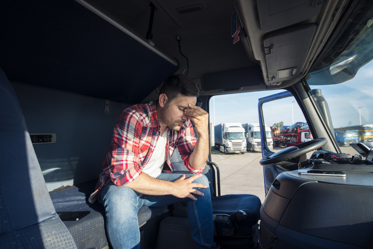 LKW-Fahrer sitzt erschöpft auf Fahrersitz - Versicherungen Berufseinsteiger