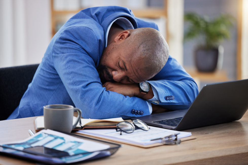 Tipps gegen Müdigkeit im Büro - Mann schläft auf Schreibtisch